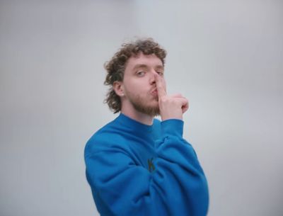 a man in a blue sweater is holding his finger to his mouth