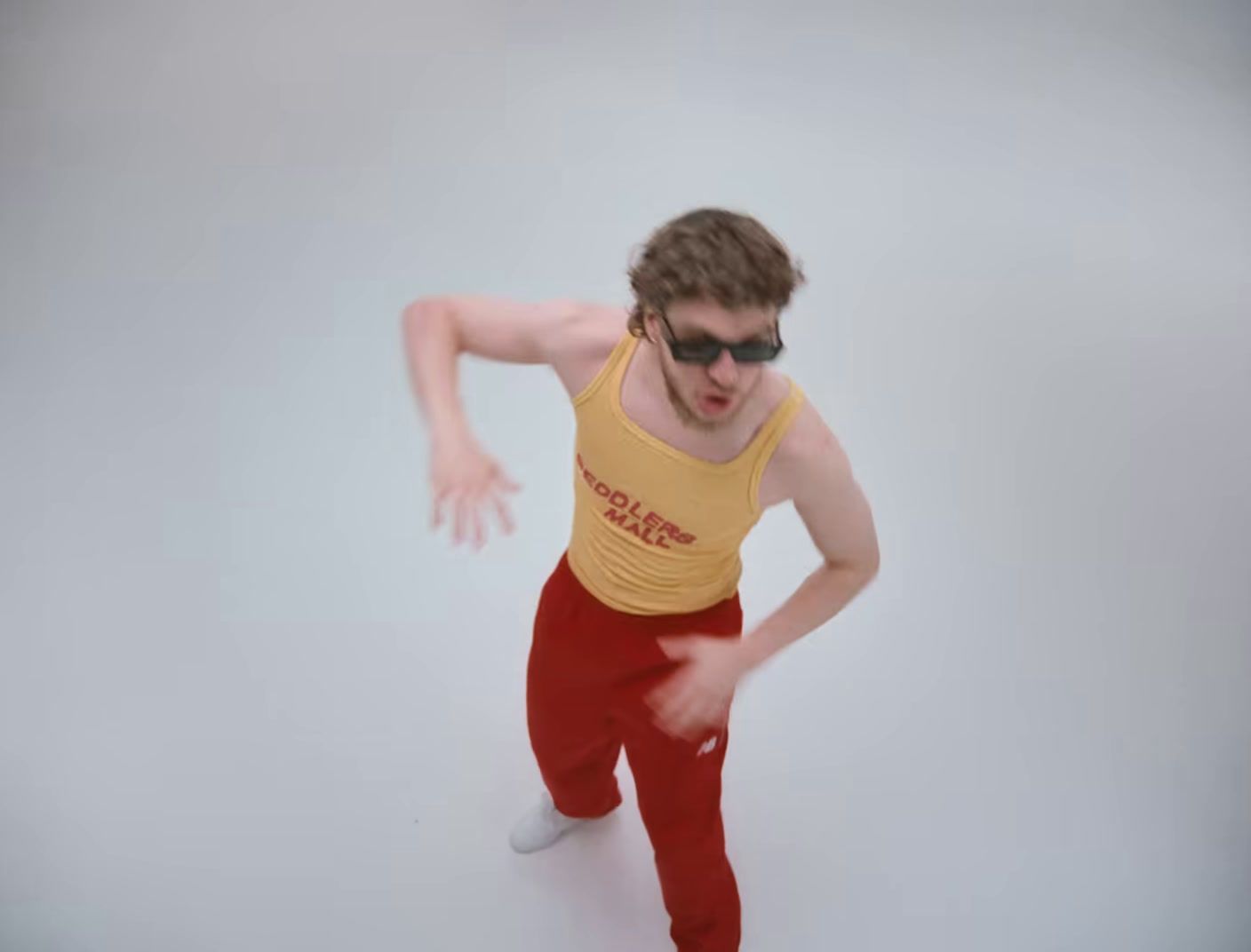 a man in a yellow tank top and red pants