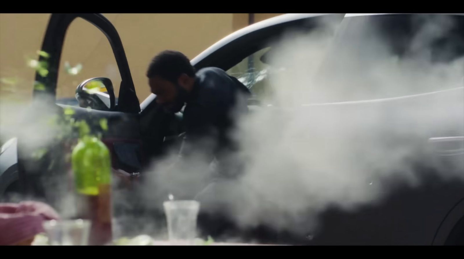 a man standing next to a car with steam coming out of it