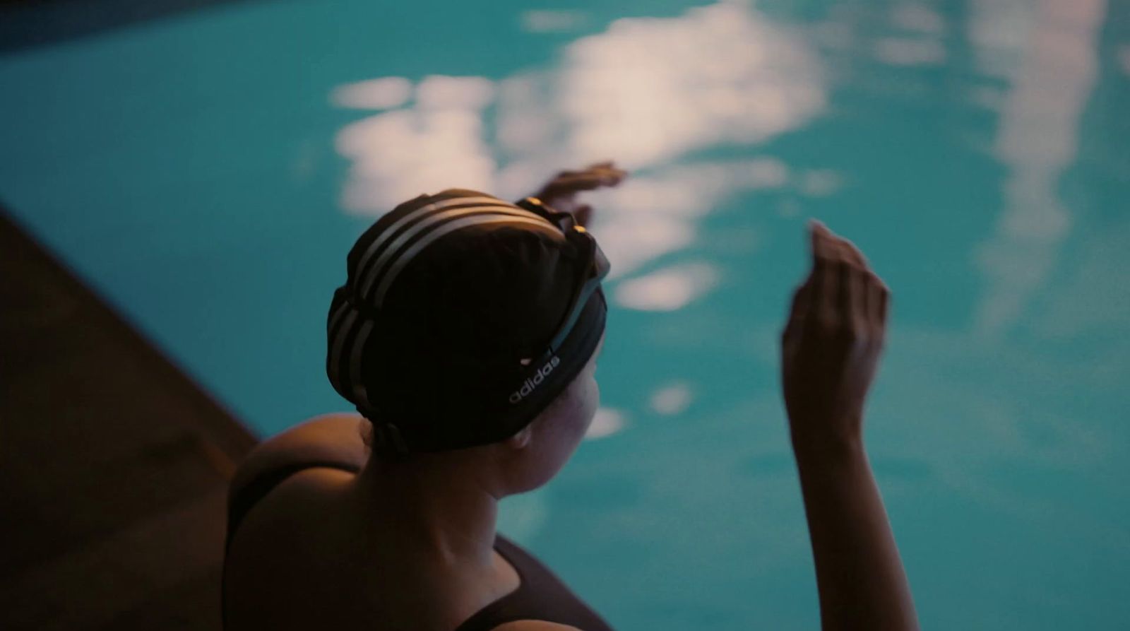 a woman in a bathing suit sitting next to a swimming pool