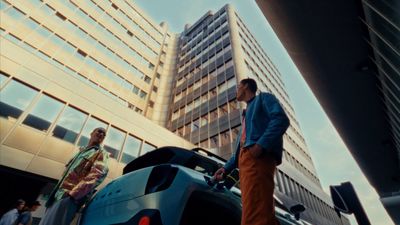 a man standing next to a car in front of a tall building