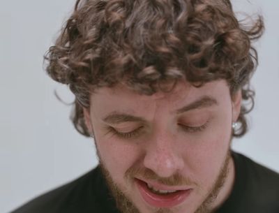 a man with curly hair is looking down at his cell phone