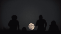 a group of people standing in front of a full moon