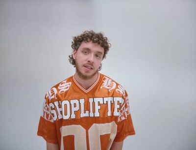 a man with curly hair wearing an orange shirt