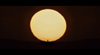 a person standing in front of a large sun