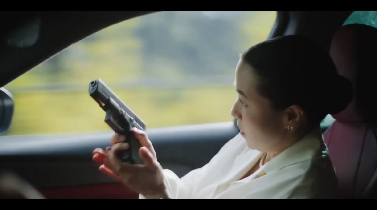 a woman sitting in a car holding a gun