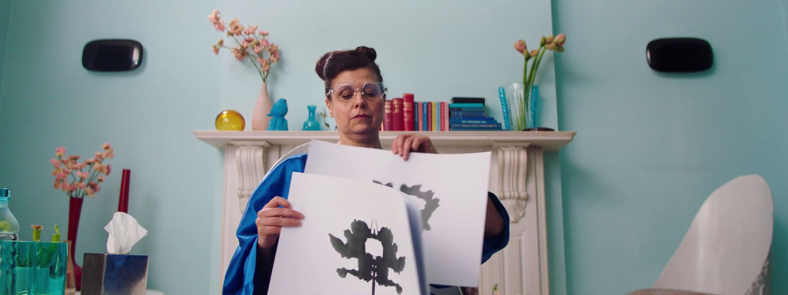 a woman holding up a piece of paper in front of a fireplace