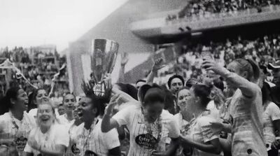 a group of women holding up a trophy in front of a crowd