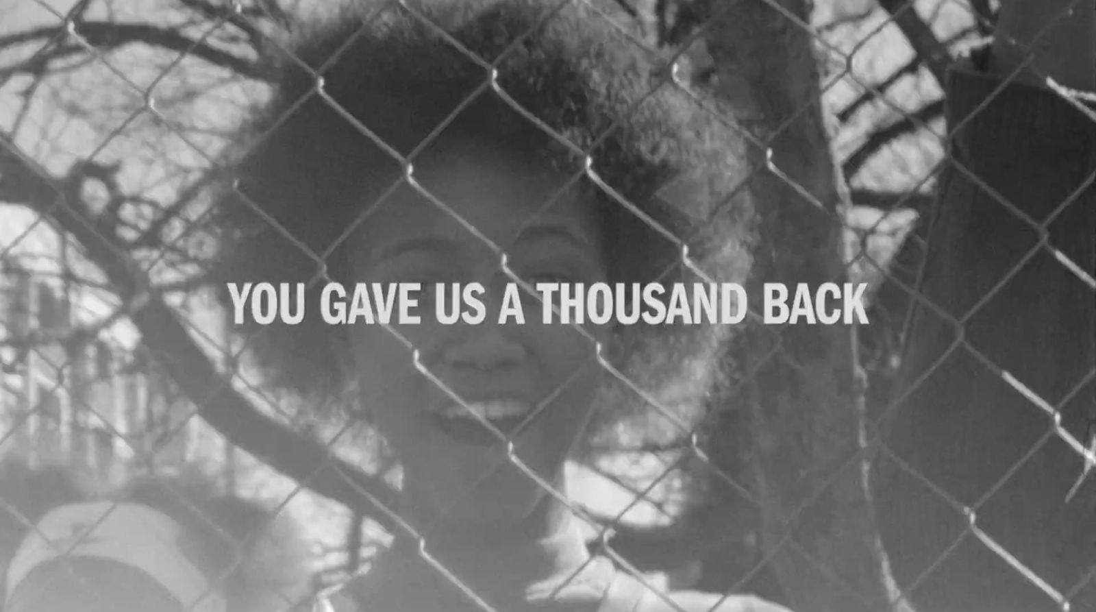 a black and white photo of a woman behind a fence