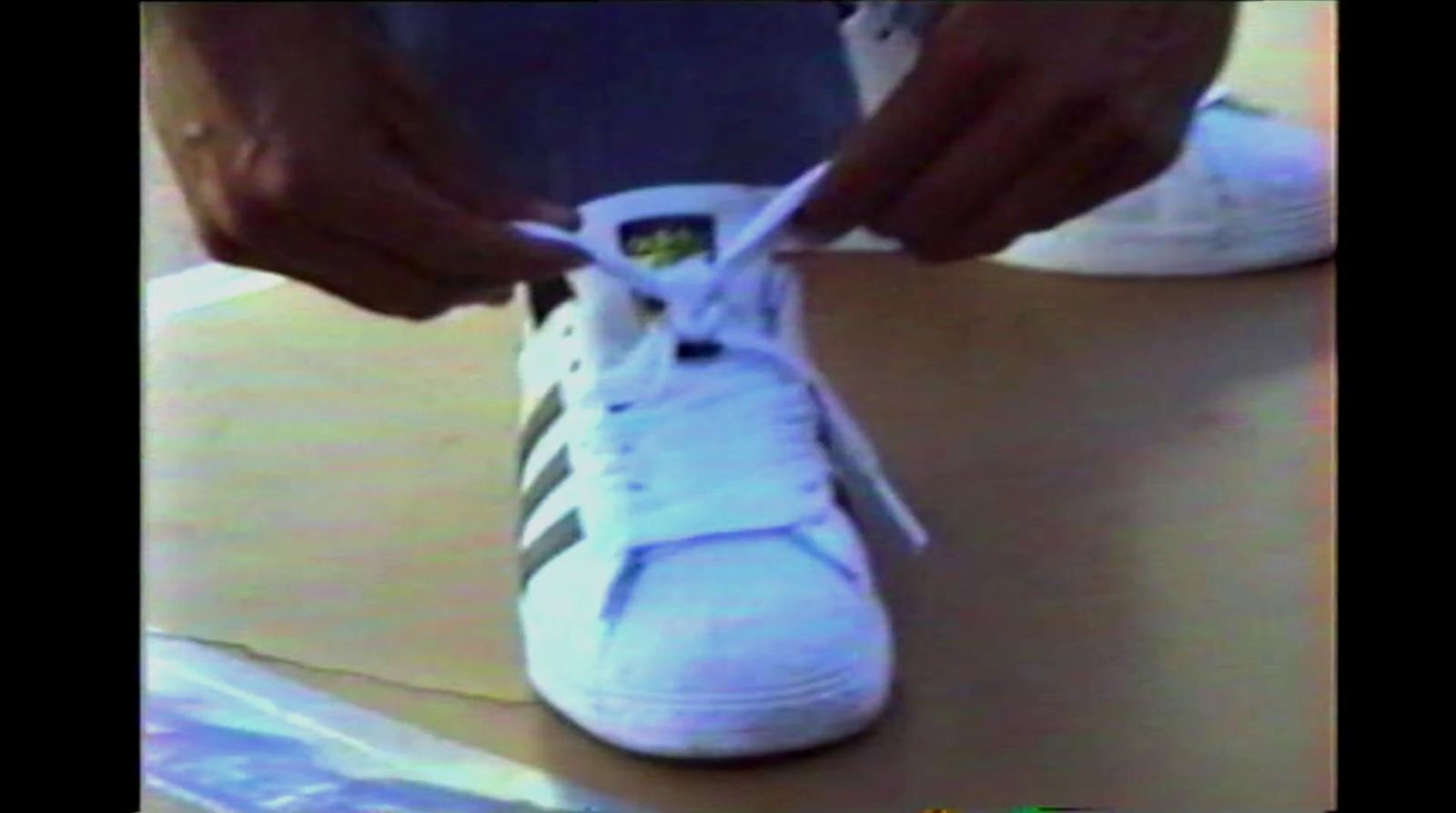 a person tying a pair of white tennis shoes