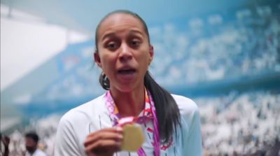 a woman holding a gold medal in front of a crowd