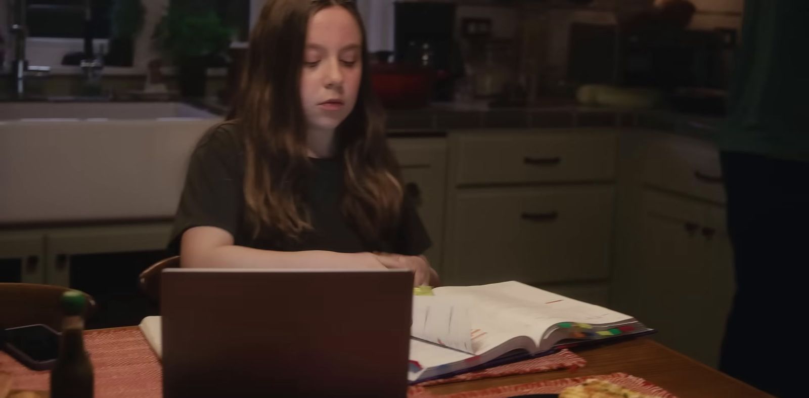 a woman sitting at a table with a laptop computer