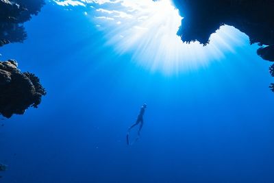 a person swimming in the water near a cave