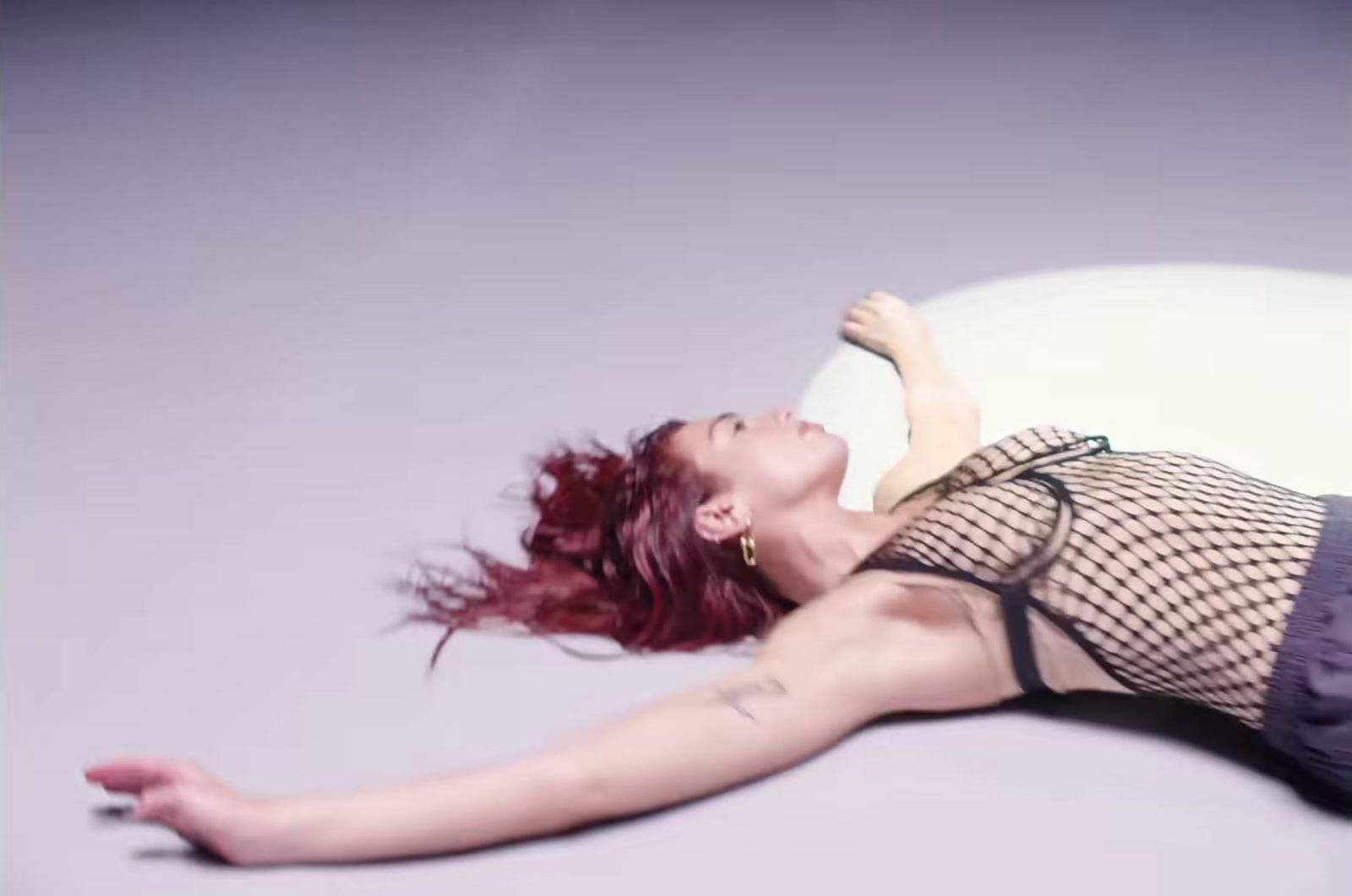 a woman with red hair laying on a white pillow