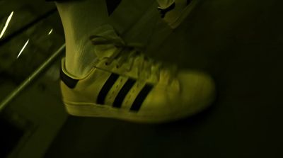 a pair of yellow adidas sneakers on a subway platform