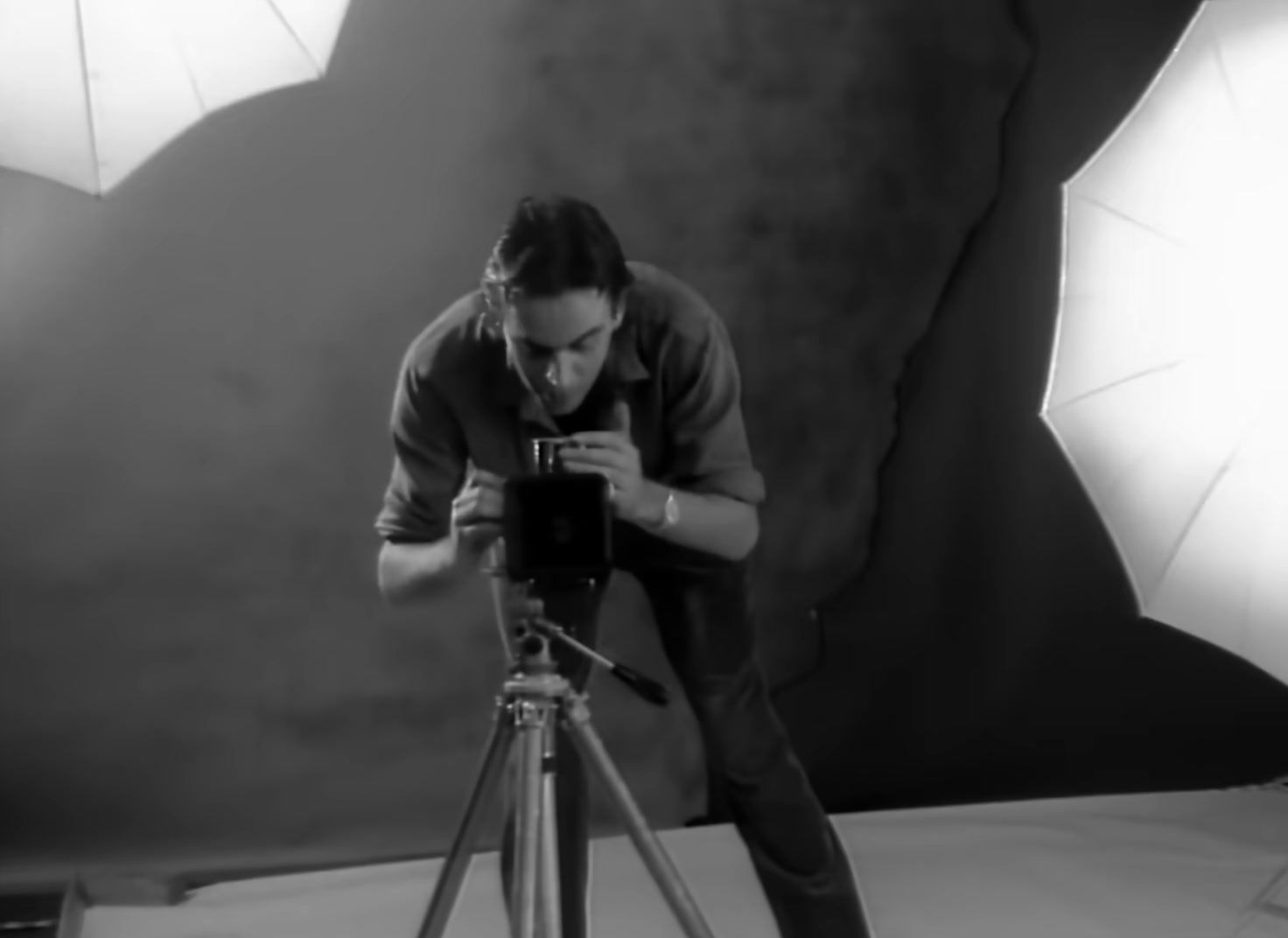 a man taking a picture of a camera on a tripod