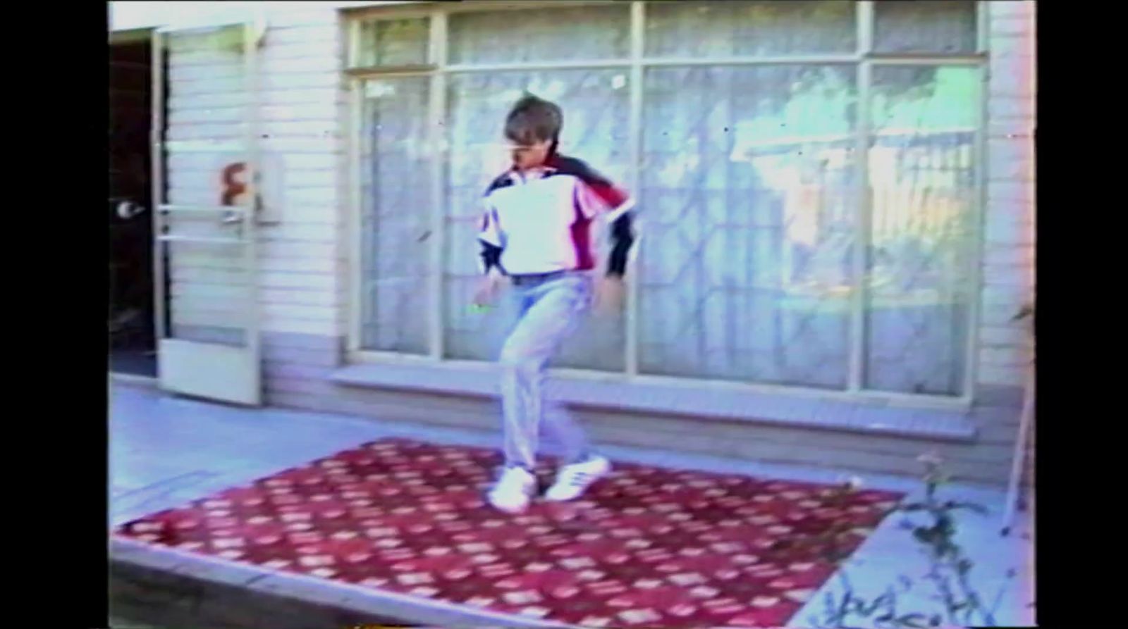 a man standing on a rug in front of a house