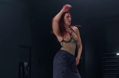 a woman with red hair is dancing in a dark room