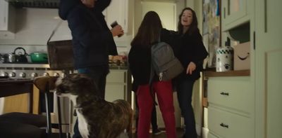 a group of people standing in a kitchen next to a dog