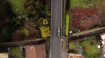 an aerial view of a street with a car parked on the side of the road