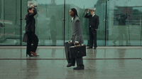 a woman walking down a sidewalk carrying a briefcase