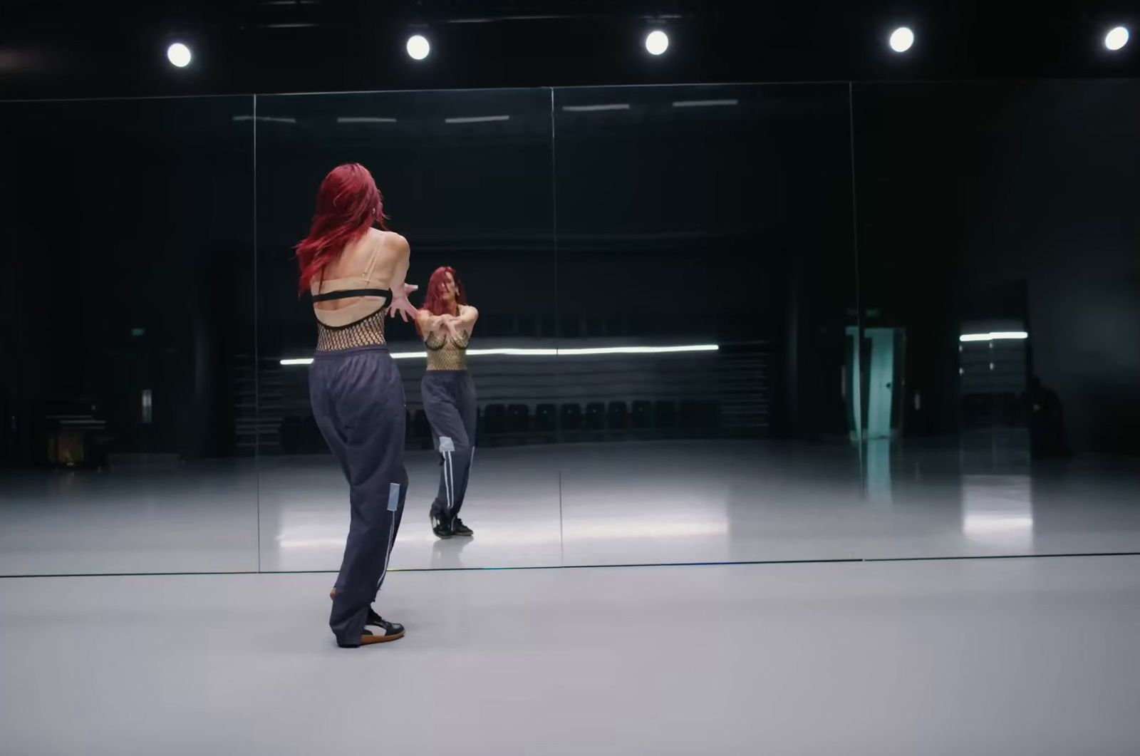 a woman with red hair standing in front of a mirror