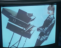 a man standing next to a piano on top of a tv