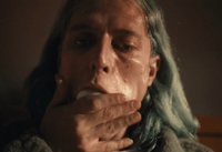 a woman with green hair is holding her hand to her mouth