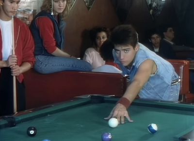 a man leaning over a pool table with a pool ball in his hand