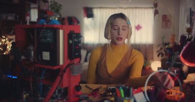 a woman sitting at a table with a lot of clutter on it