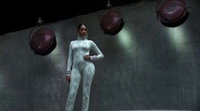 a woman in a white outfit standing in front of a wall