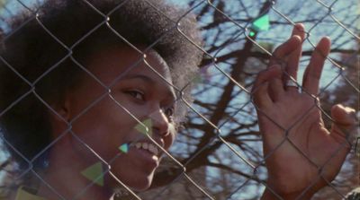 a woman standing behind a chain link fence