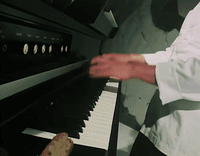 a man in a white shirt is playing a piano