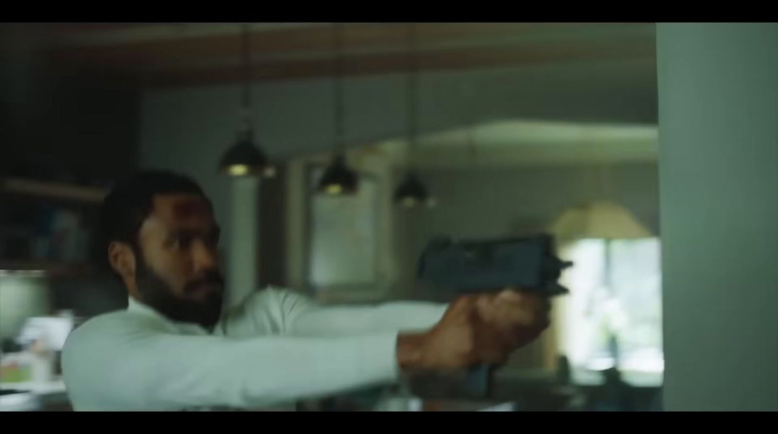 a man holding a gun in a kitchen