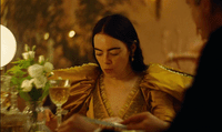 a woman sitting at a table with a glass of wine