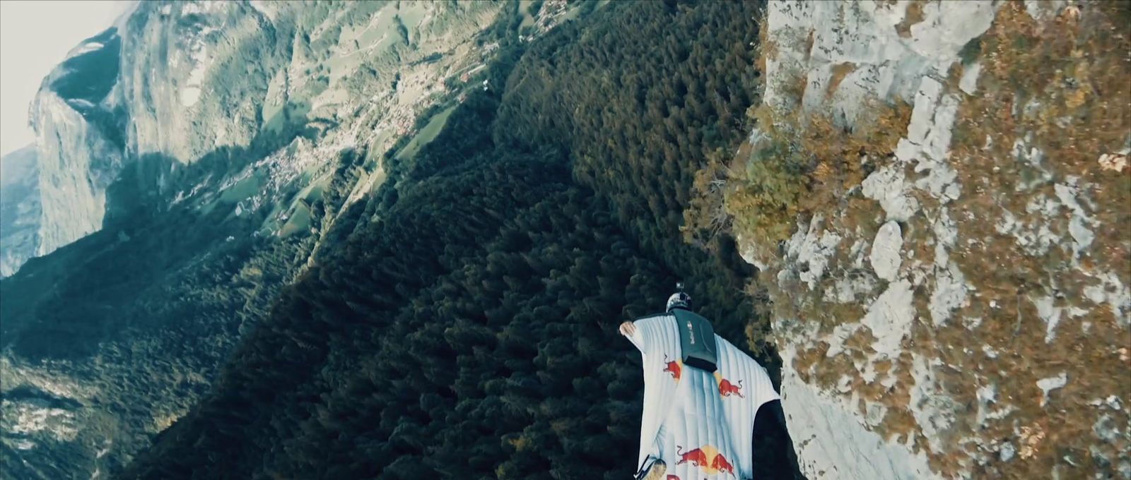 a man standing on top of a cliff next to a mountain