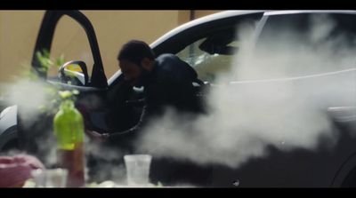 a man standing next to a car with smoke coming out of it