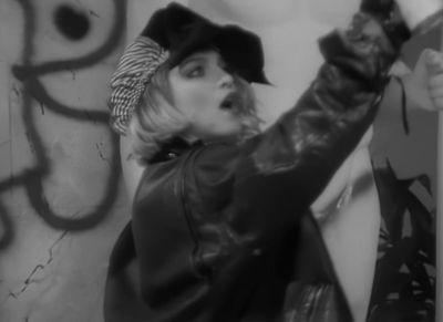 a woman in a hat and leather jacket holding a sign