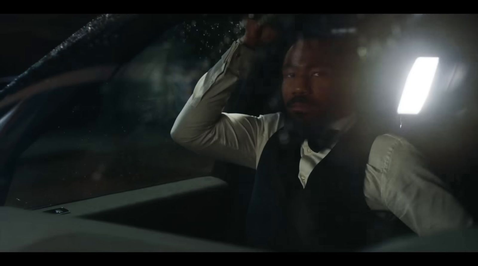 a man sitting in a car with his hand on his head