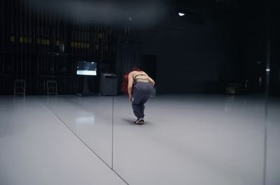 a man walking across a white floor in a dark room