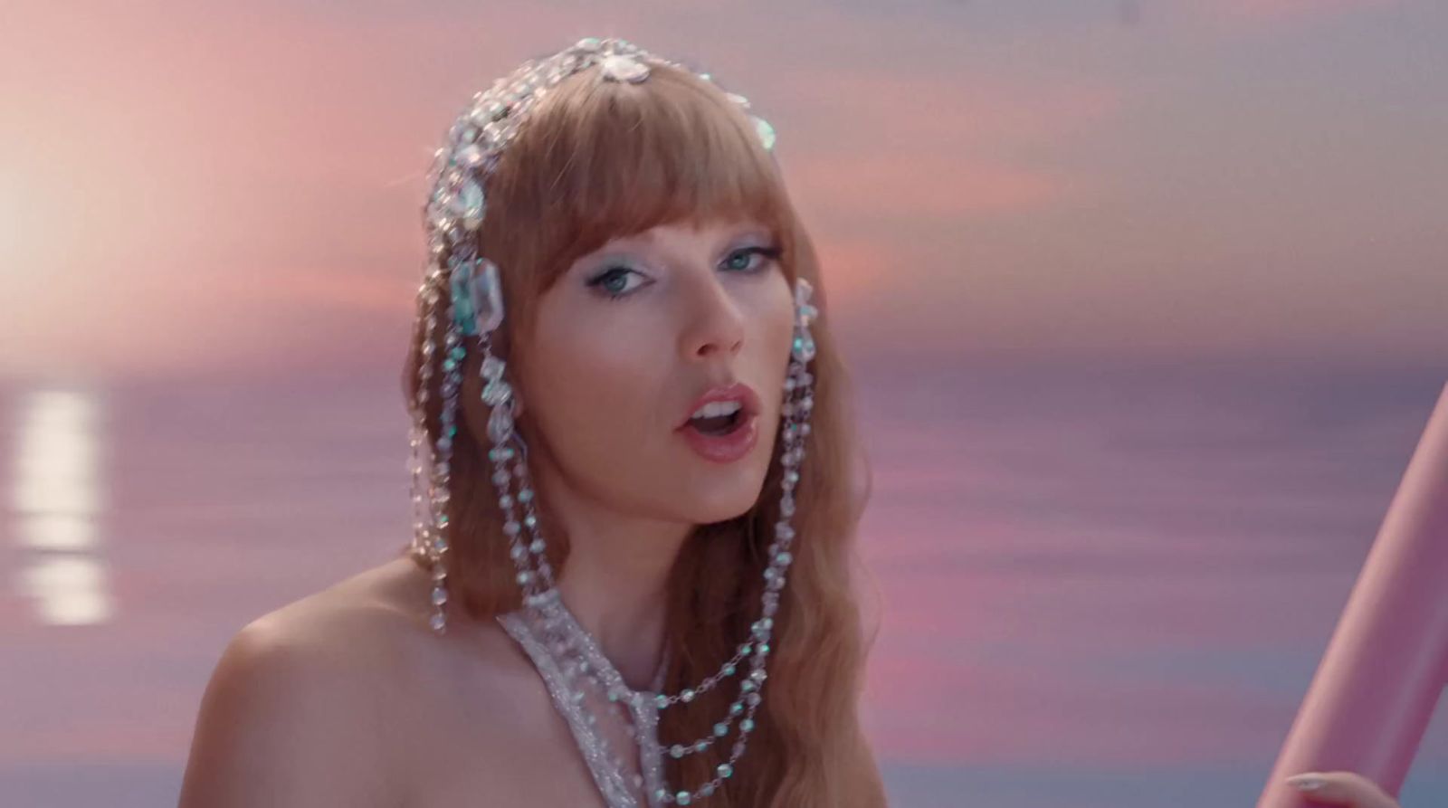 a woman with pearls on her head holding a pink umbrella