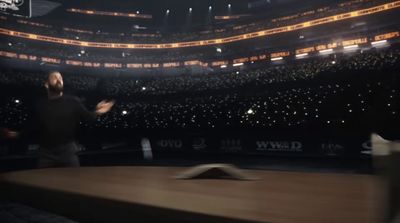 a man standing in front of a wooden table in a stadium