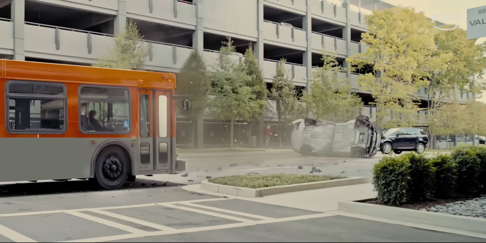 an orange and gray bus driving down a street next to a tall building