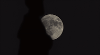 a shadow of a person standing in front of a full moon