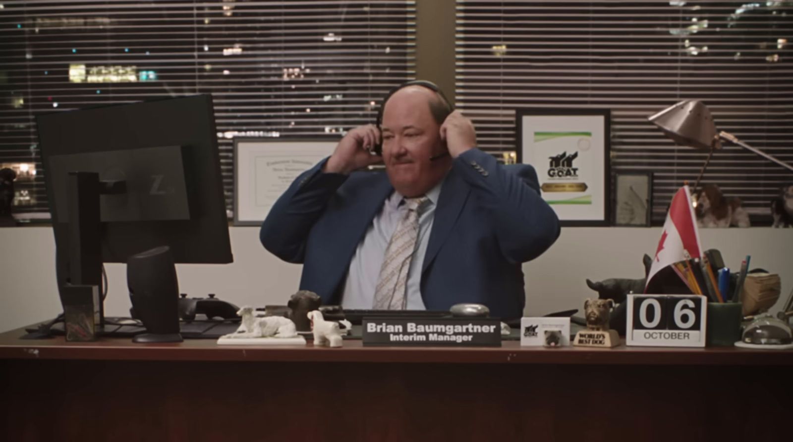 a man sitting at a desk talking on a cell phone