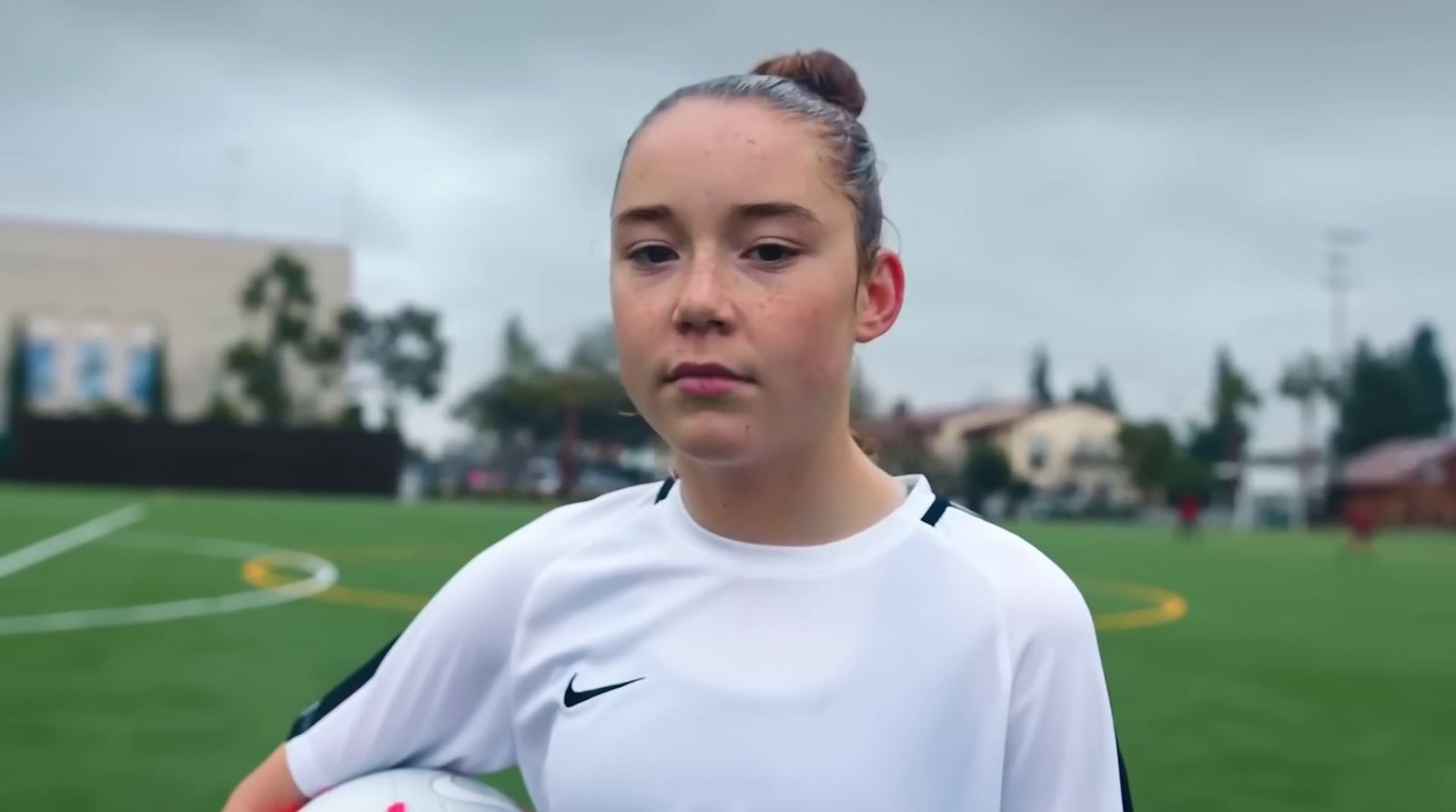 a young girl holding a soccer ball on a soccer field