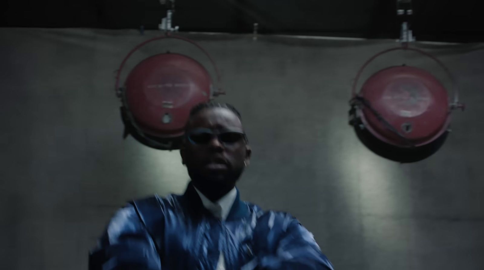 a man in a suit and sunglasses standing in front of a wall with two red