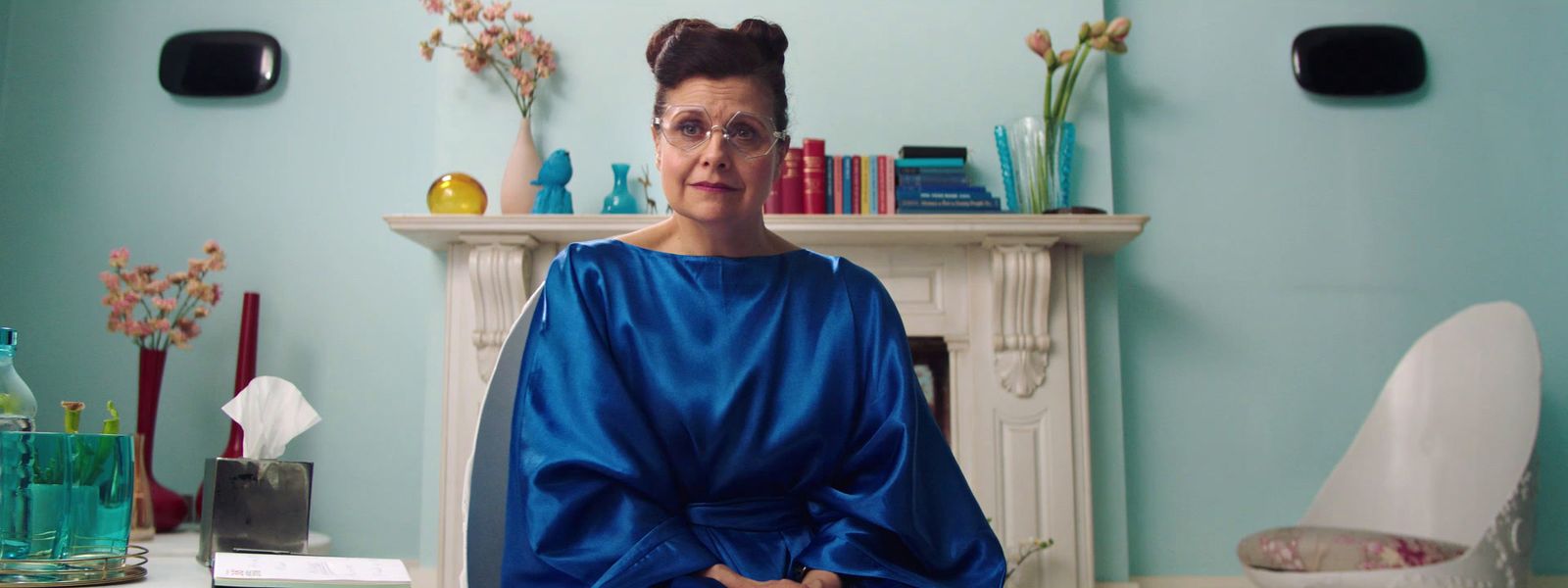 a woman in a blue dress standing in front of a fireplace