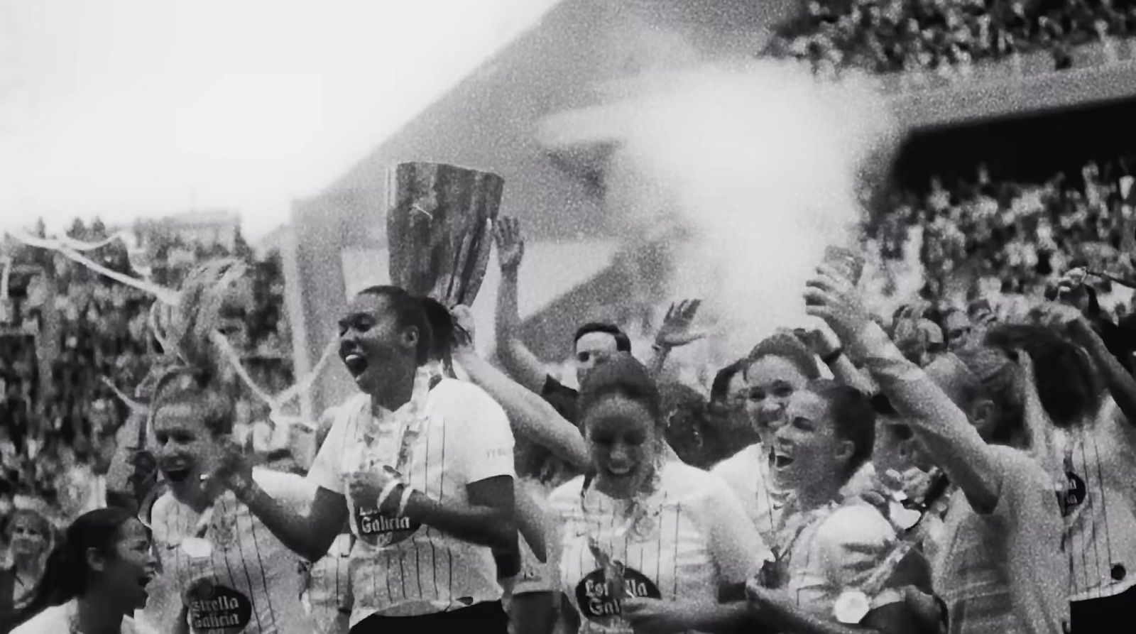 a group of women holding up a trophy in front of a crowd