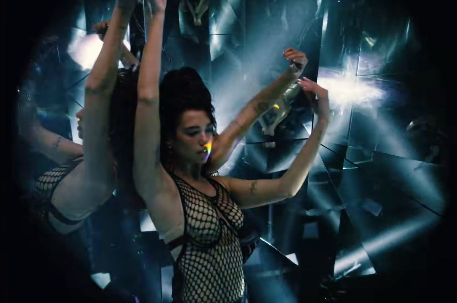 a woman in a fishnet bodysuit dancing in front of a mirror